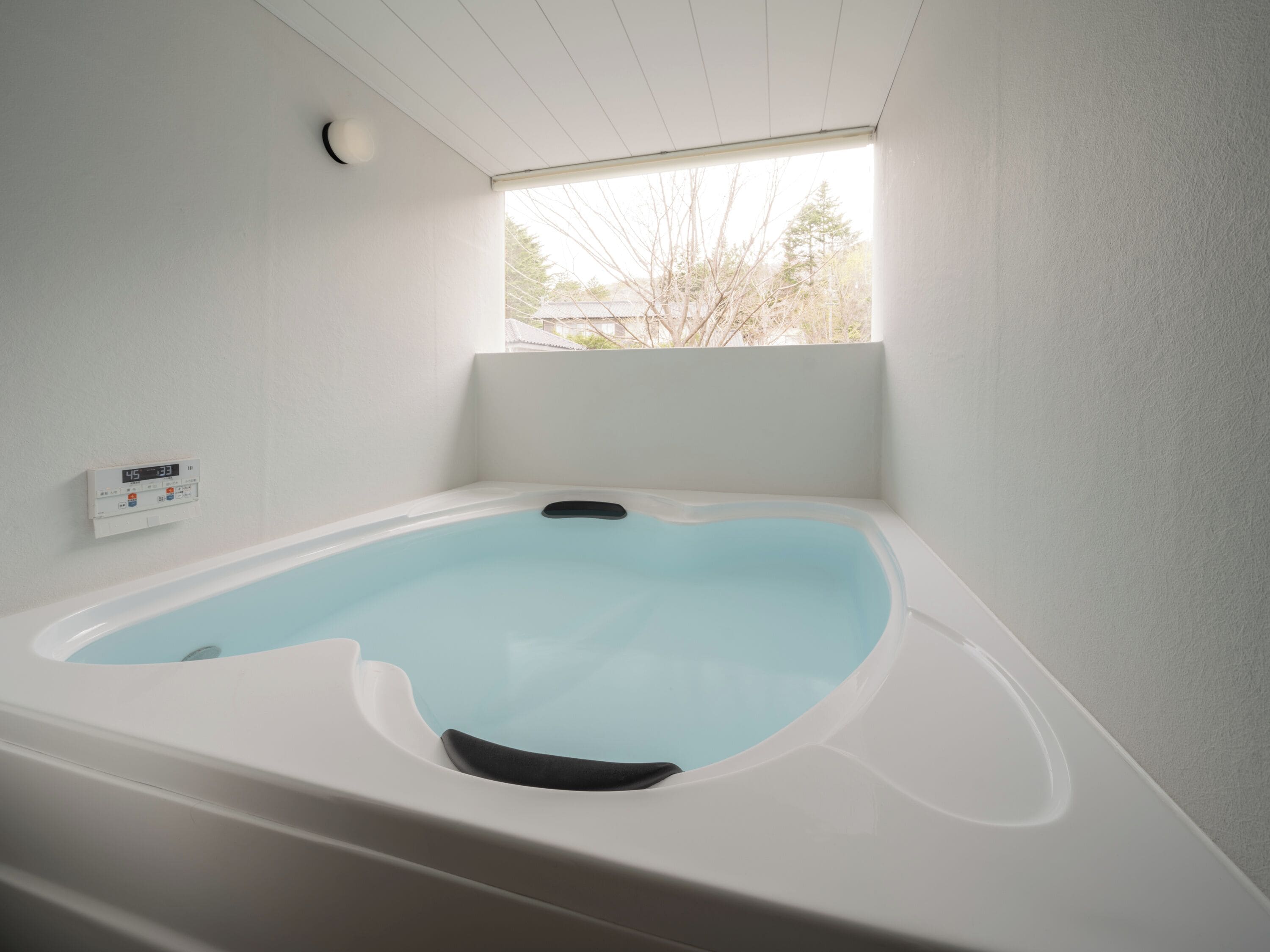 A modern bathroom with a freestanding bathtub, a built-in heater, and a window providing natural light.