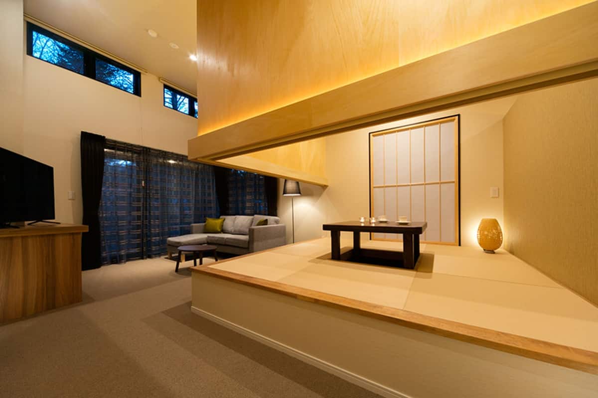 Ein modernes Wohnzimmer mit einem Holzbüro, einer Couch, einem Tisch und einem traditionellen japanischen Raumteiler.