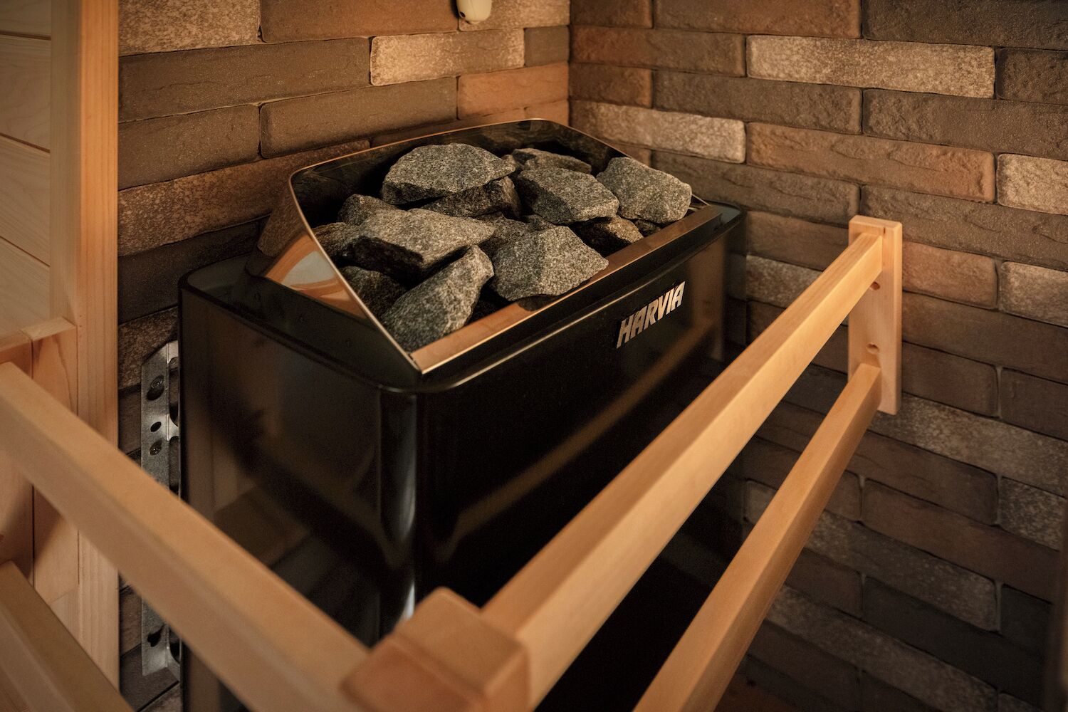 A black storage unit labeled 'HARVIA' with a wooden frame, containing several rocks.
