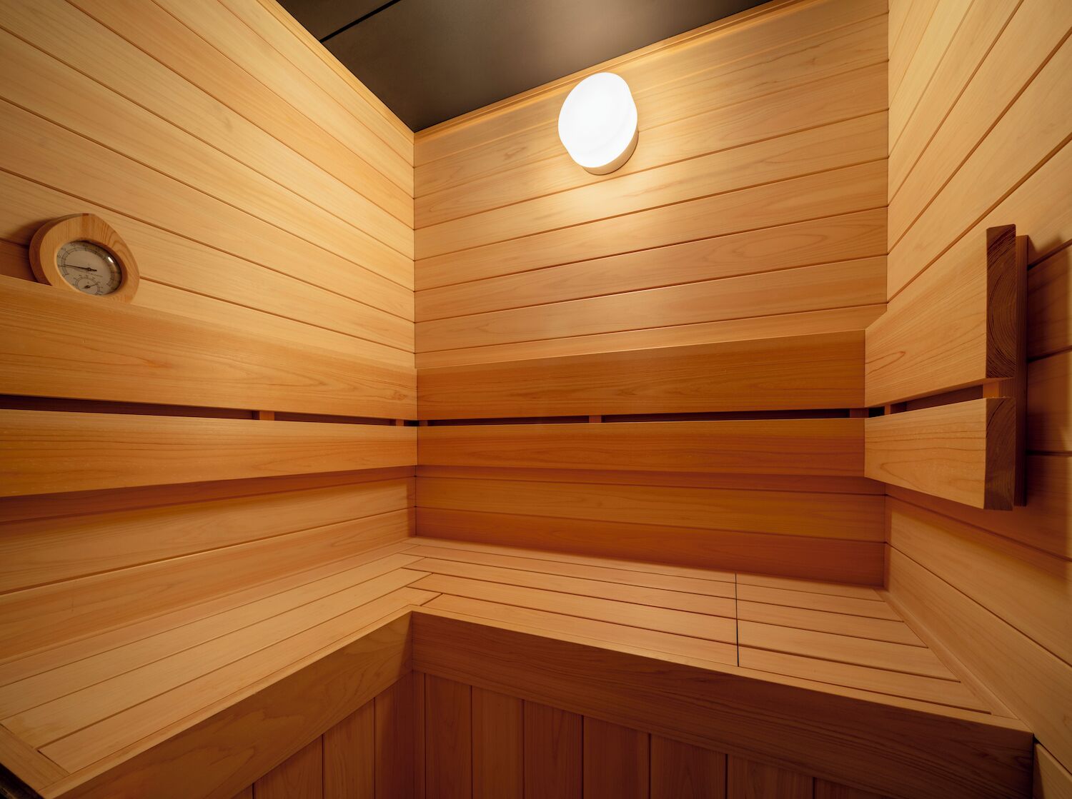 A sauna with wooden walls and a circular light fixture.