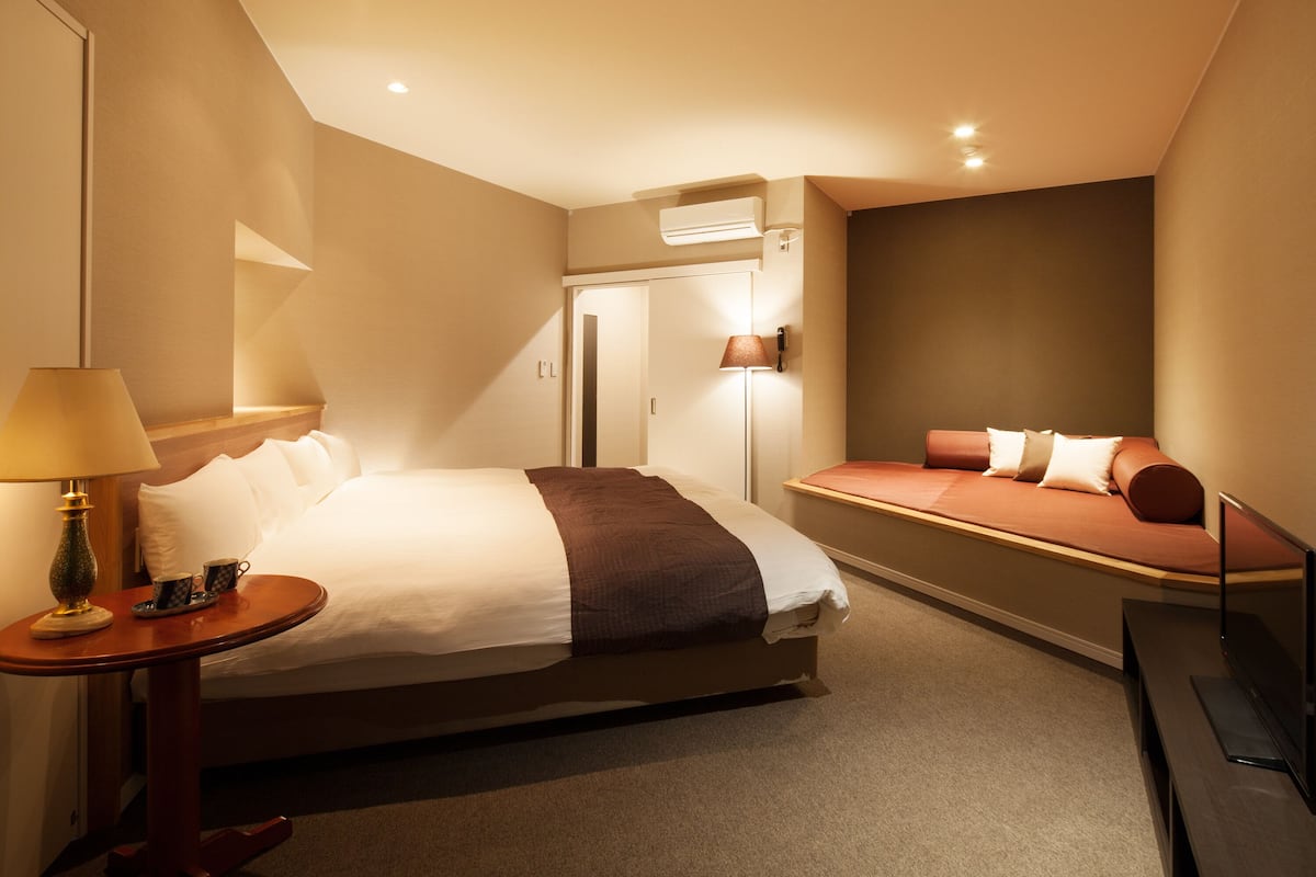 Ein Hotelzimmer mit Bett, Nachttisch, Lampe und Schlafsofa.