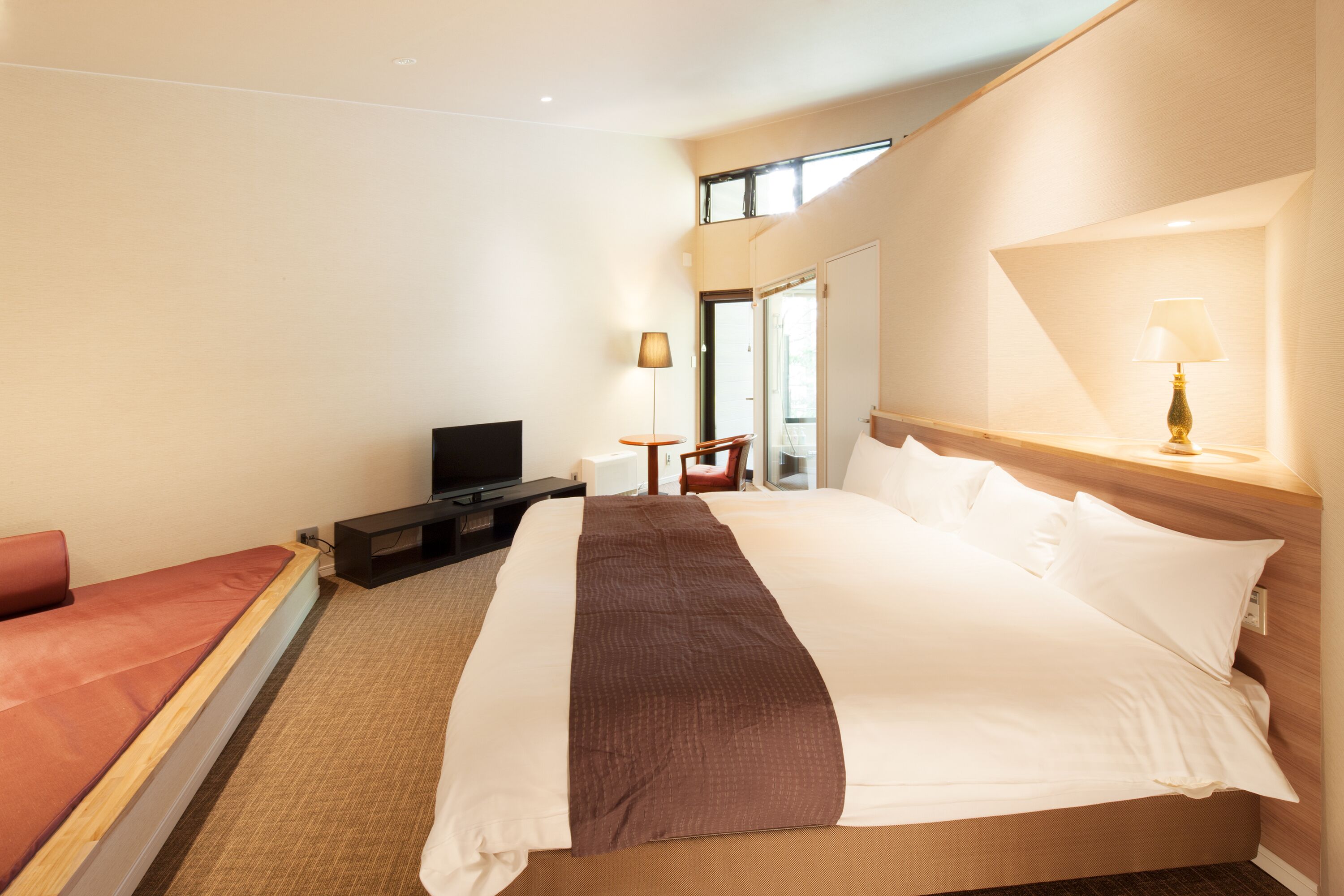 Habitación de hotel con una cama grande, televisión, escritorio y una silla.