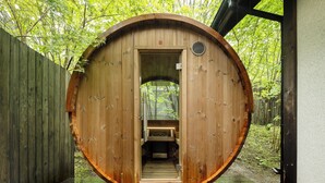 A wooden sauna structure with a bench inside, surrounded by a wooden fence and trees. - Karuizawa Hotel Longing House (Karuizawa)