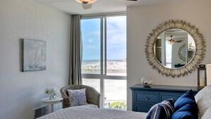Ein Schlafzimmer mit einem Bett, einem Sessel, einem Schminktisch, einem Spiegel und einem Deckenventilator.