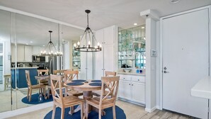 Eine moderne Küche mit Essbereich, ausgestattet mit einer zentralen Kochinsel, Holzstühlen und einer Kronleuchter.
