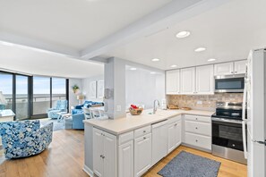A modern kitchen with white cabinets, a stainless steel oven, and a large island.