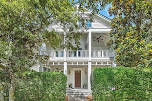 A two-story house with a porch, a front door, and a small garden area. - Luxurious WaterColor Estate! Private Pool, Carriage House, Near Beach! Ideal For Large Groups! (Santa Rosa Beach)