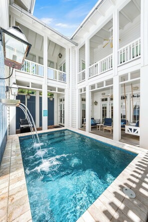 A pool area with a hot tub, lounge chairs, and a covered deck.