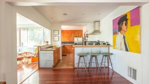 A modern kitchen with a central island, wooden cabinets, and bar stools. - Silver Lake Mid-century Nestled in the Treetops (Los Angeles)