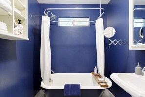 A bathroom with a bathtub, a sink, and a shower area. - Silver Lake Mid-century Nestled in the Treetops (Los Angeles)