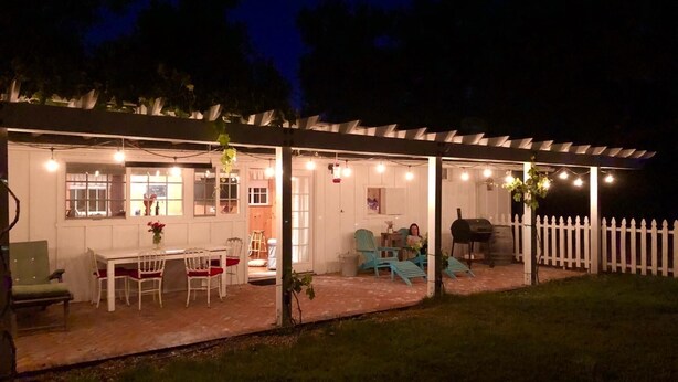A covered patio area with a table and chairs, a grill, and string lights. - Charming Santa Ynez farmhouse (Santa Ynez)