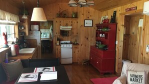 A cozy cabin-style kitchen with wooden walls, a stove, and a red cabinet. - Charming Santa Ynez farmhouse (Santa Ynez)