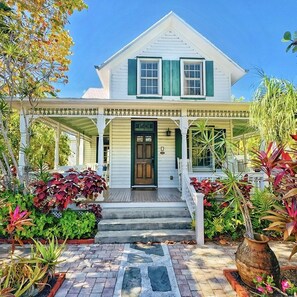 A two-story house with a porch, a front door labeled '1501', and a well-maintained garden with various plants.