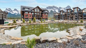 Un hôtel moderne à plusieurs étages, doté d’une cour intérieure avec un bassin, et offrant une vue sur les montagnes en arrière-plan.