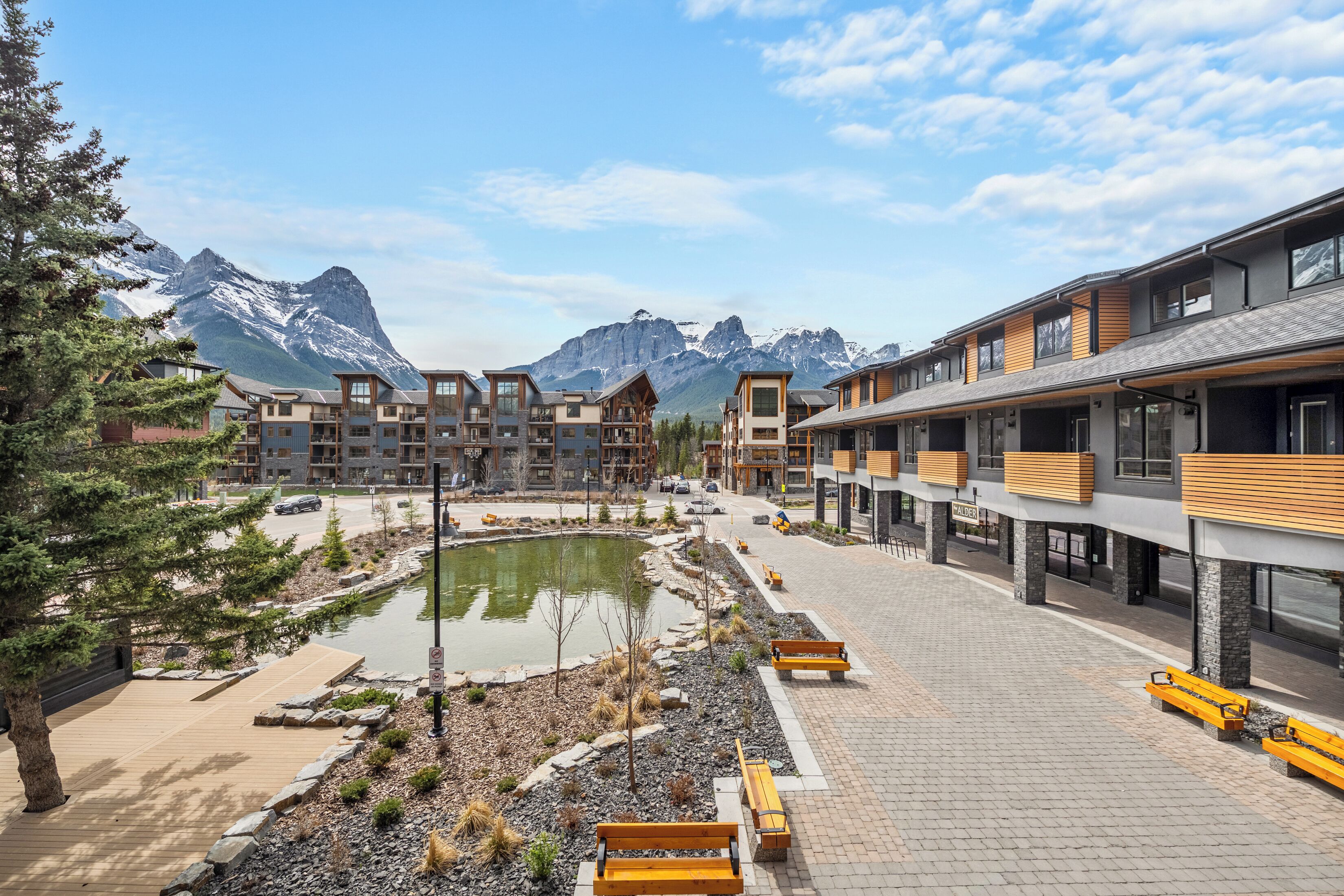 A modern hotel with a central courtyard, outdoor seating, and mountain views.