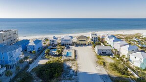 A coastal residential area with beachfront properties, a swimming pool, and a beach in the background.