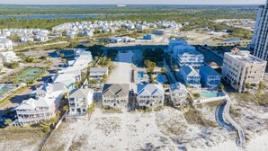 A coastal residential area with multiple two-story houses, a large swimming pool, and a beach.