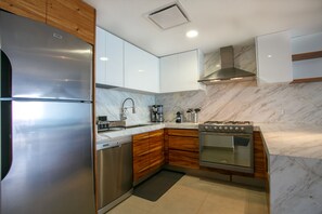 A modern kitchen with stainless steel appliances, wooden cabinets, and marble countertops. - Luxurious, Beachfront 2bed/2 bath Condo with Designer Finishes (Puerto Vallarta)