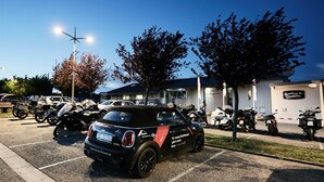 A parking lot with several motorcycles and a black car. - Hostellerie Du Chambellan (Pontpierre)