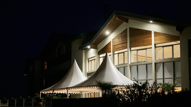 A modern building with a large, illuminated tent structure in front. - Hostellerie Du Chambellan (Pontpierre)