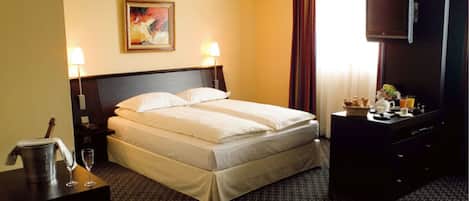 A hotel room with a bed, two bedside lamps, a television, a dresser, and a painting on the wall.
