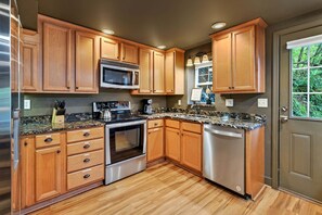 A kitchen with wooden cabinets, a stainless steel refrigerator, a microwave, an oven, and a dishwasher.