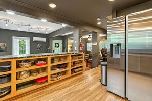 A kitchen with wooden shelves, a stainless steel refrigerator, and a water dispenser.