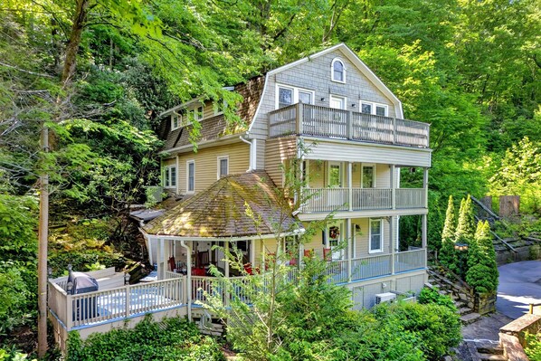A multi-story house with a porch, surrounded by dense greenery.