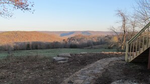 A stone pathway leading to a wooden staircase in a natural setting with a view of hills and trees. - Lost Valley View Cabin (Ponca)