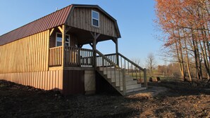 A wooden structure with a porch and stairs leading up to a window. - Lost Valley View Cabin (Ponca)