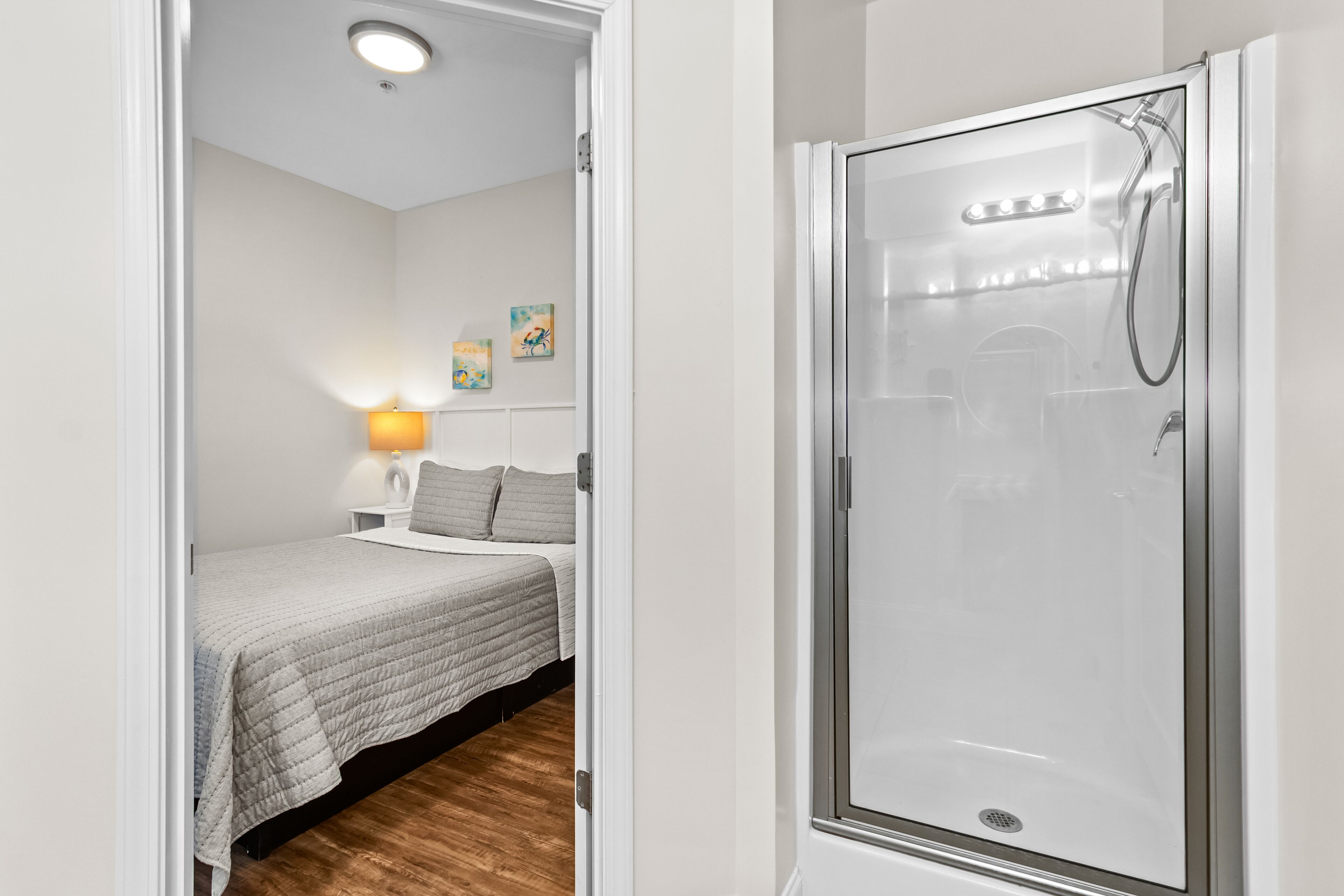Une chambre à coucher comprenant un lit, une table de chevet, une lampe et un espace douche.