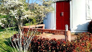 A traditional yurt with a red door, surrounded by a garden with flowering plants and a bench. - The Natural Yurt Resort at Khao Kho (Khao Kho)