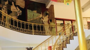 A grand staircase with golden railings and a marble floor, leading to an upper level with traditional artwork. - The Natural Yurt Resort at Khao Kho (Khao Kho)