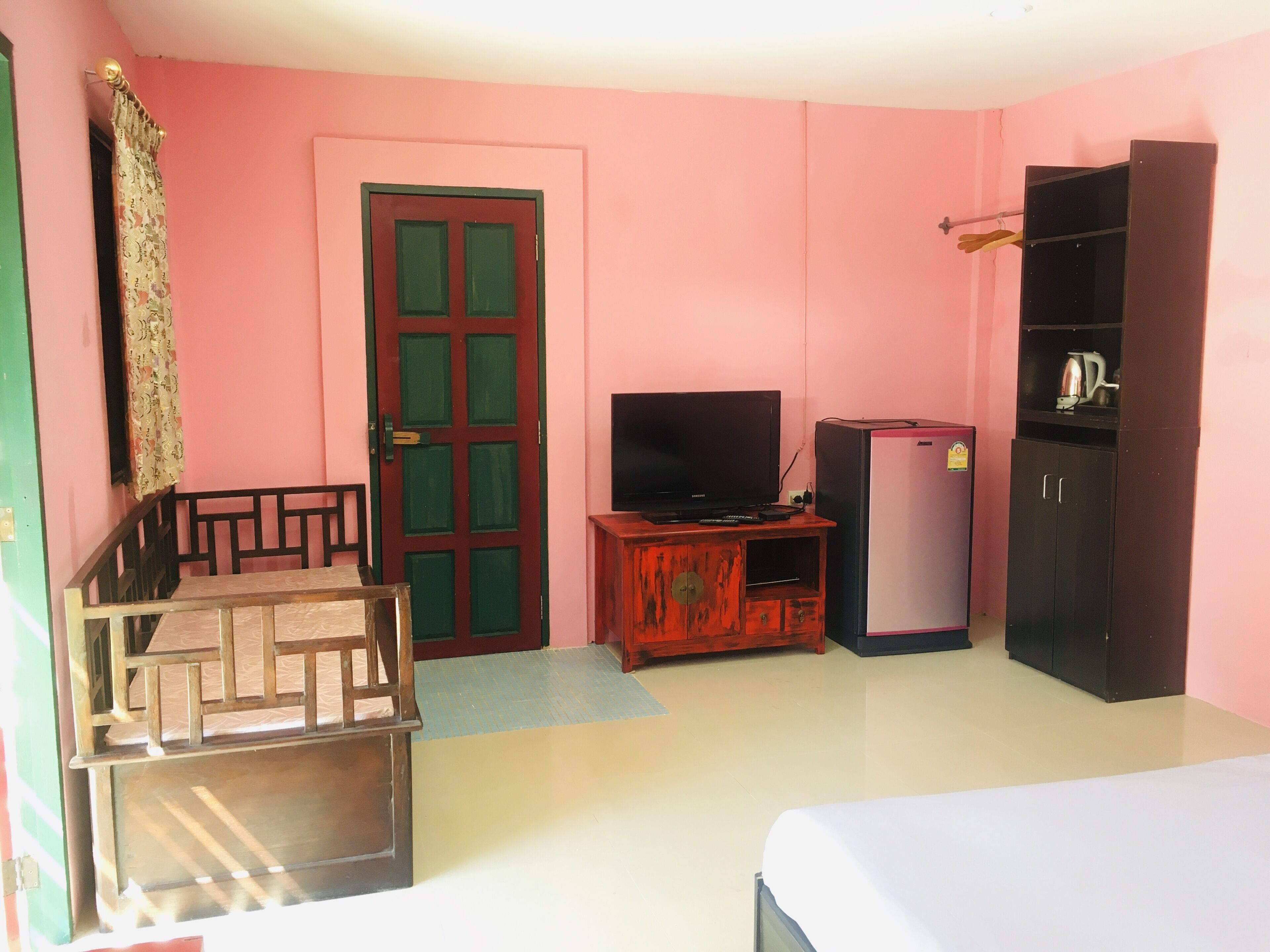 A room with a bed, a TV, a refrigerator, and a wardrobe.