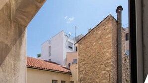 Una calle estrecha flanqueada por edificios, uno con tejado rojo y otro con fachada de piedra.