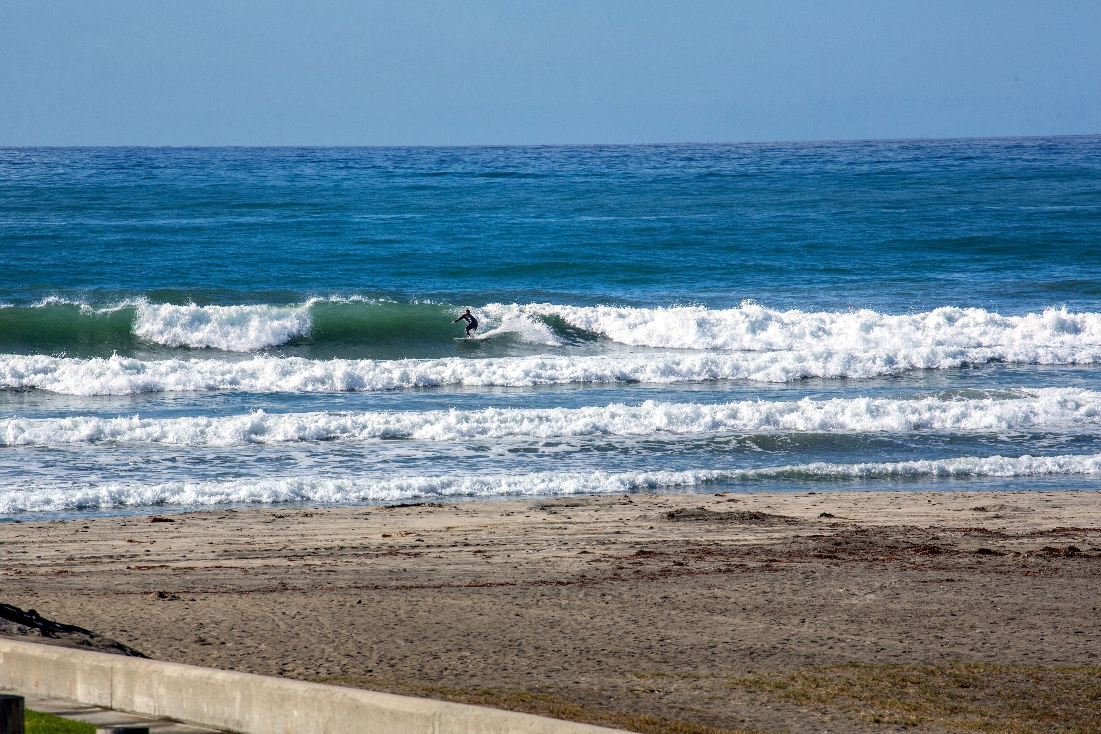 A beach with waves and a surfer.