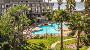 Ein Resort mit Pool, Palmen und Blick auf den Ozean.