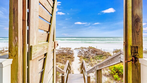 A wooden staircase leading to a beach with a clear view of the ocean.