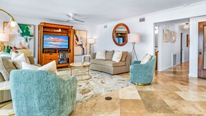 A spacious living room with a large flat-screen TV, comfortable seating, and a decorative rug.
