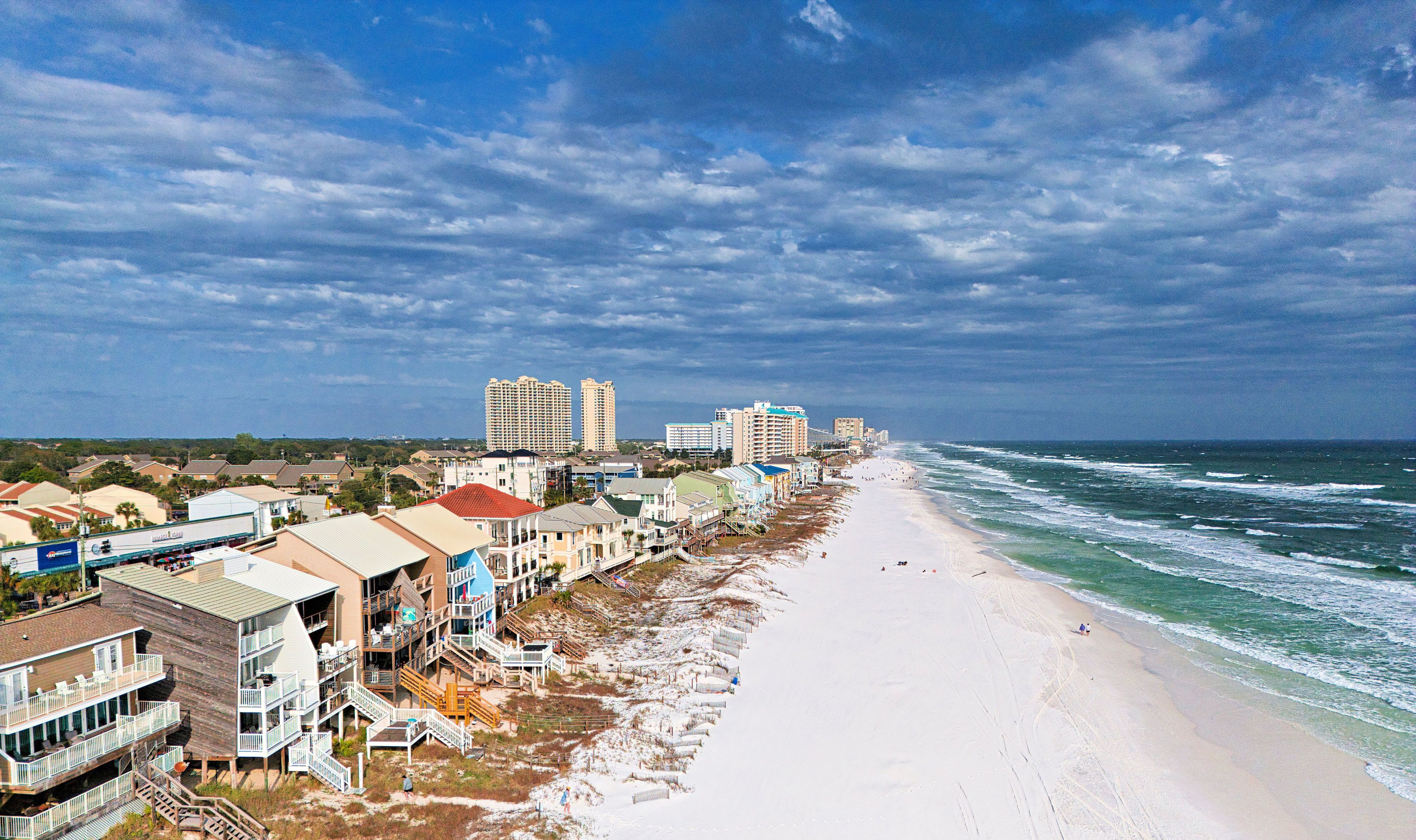 A beachfront hotel with multiple stories, a sandy beach, and ocean waves.