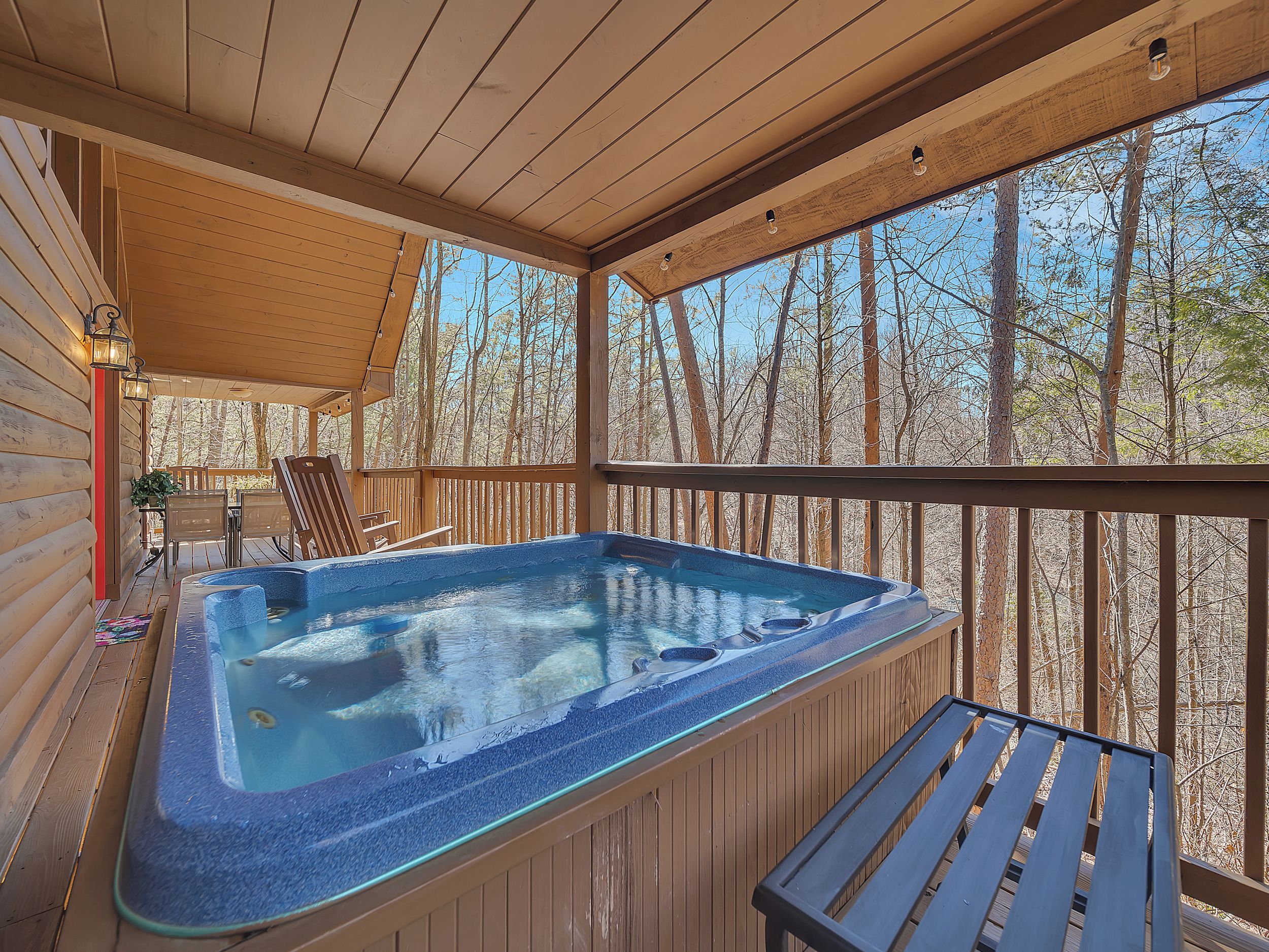 A hot tub on a wooden deck with a view of trees.