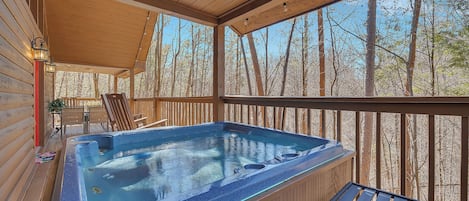 A hot tub on a wooden deck with a view of trees.