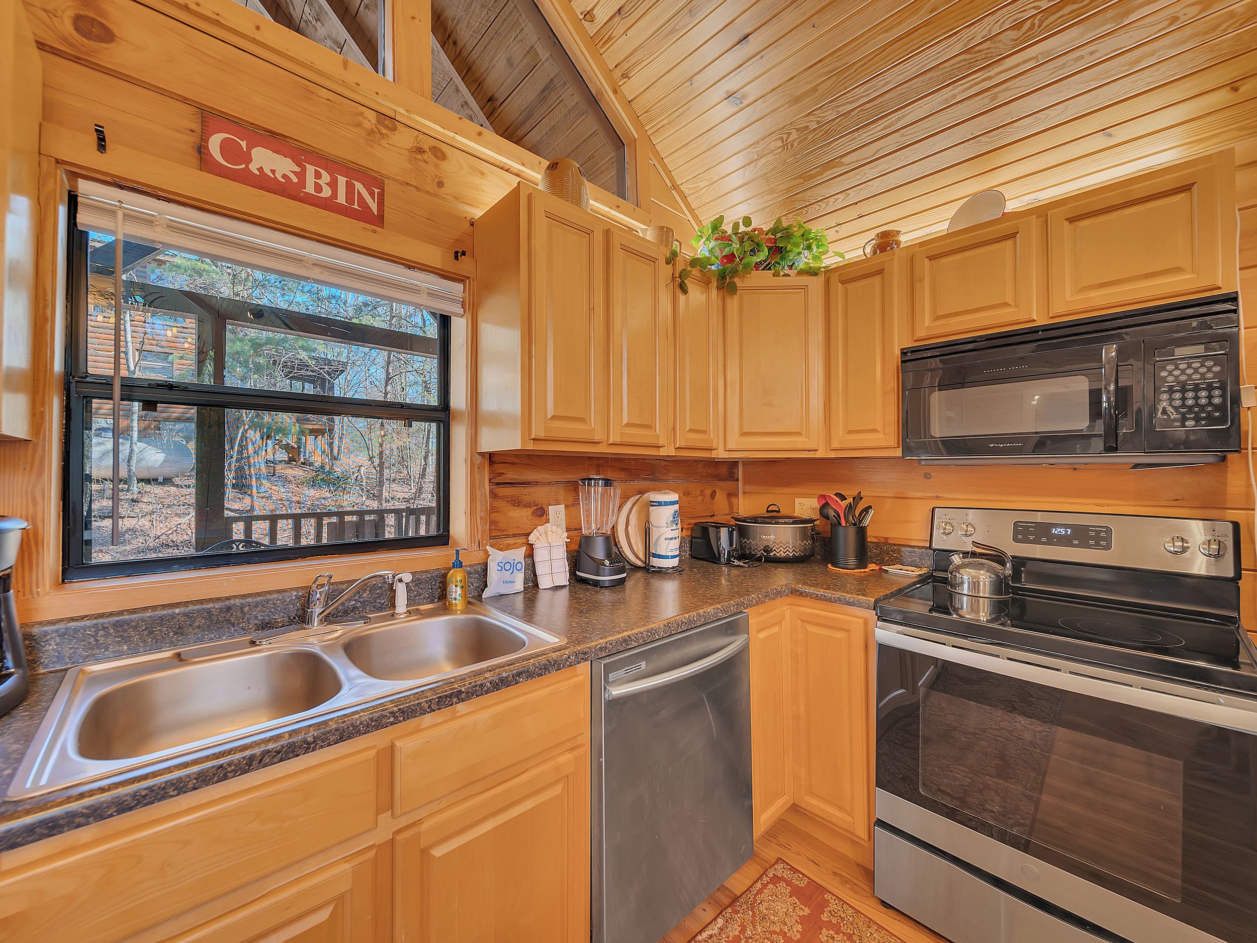 A kitchen with wooden cabinets, a sink, a dishwasher, a stove, and a microwave.
