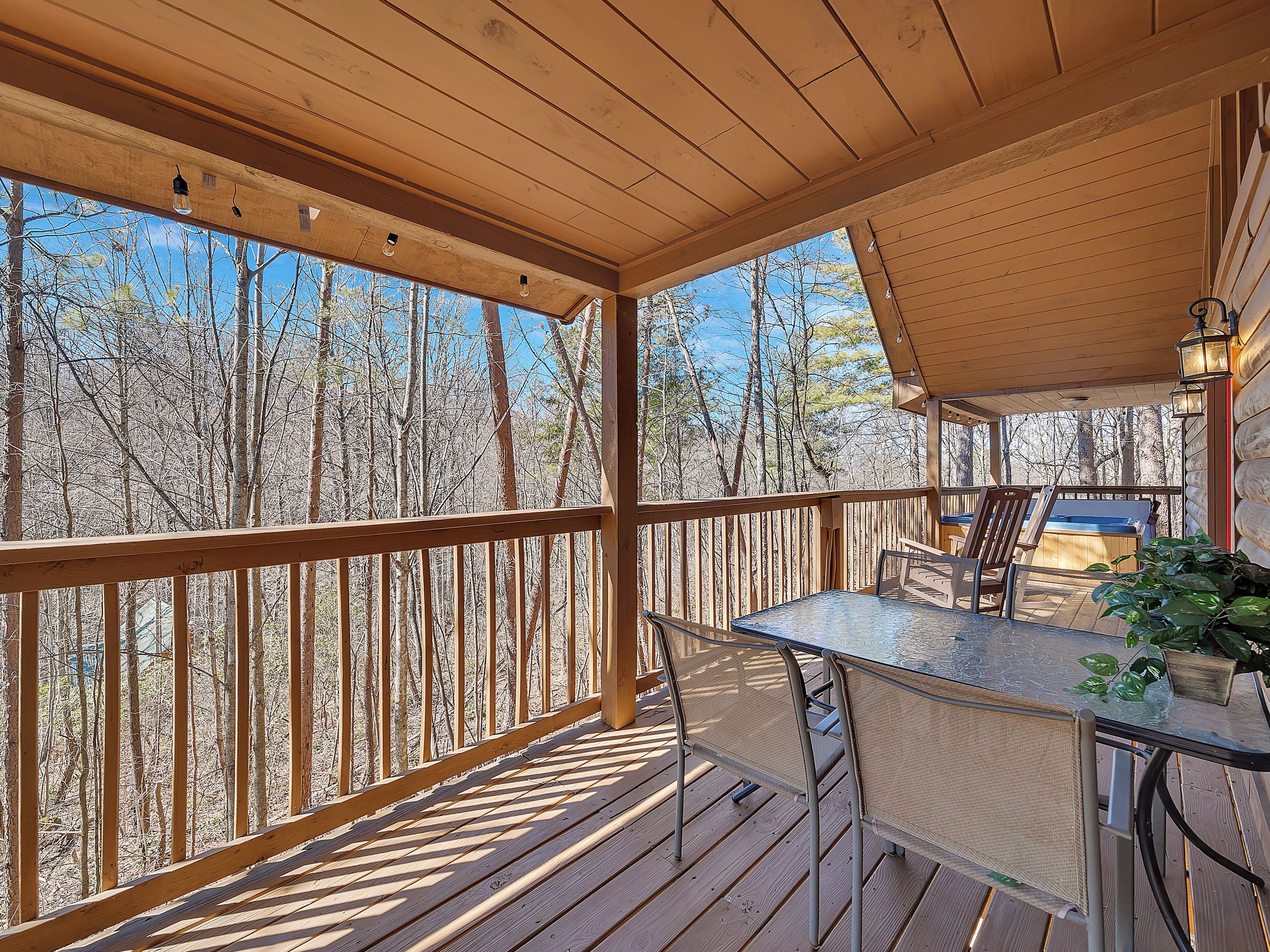 A wooden deck with a table and chairs, overlooking a forested area.