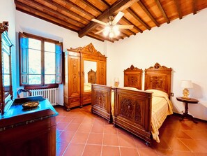 A bedroom with a wooden ceiling, a large wardrobe, a bed, a nightstand, and a window with a view. - A Panoramic Tuscan Luxury - Villa Maria in Fronzano (Reggello)
