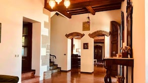 A spacious living area with a wooden floor, a staircase, and a dining area in the background.