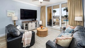A living room with a flat-screen TV, a ceiling fan, a round coffee table, and a sofa. - Ocean Front 3 BR/3BA/Ground Floor walk out Updated (Fort Walton Beach)