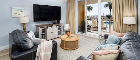 A living room with a flat-screen TV, a ceiling fan, a round coffee table, and a sofa.