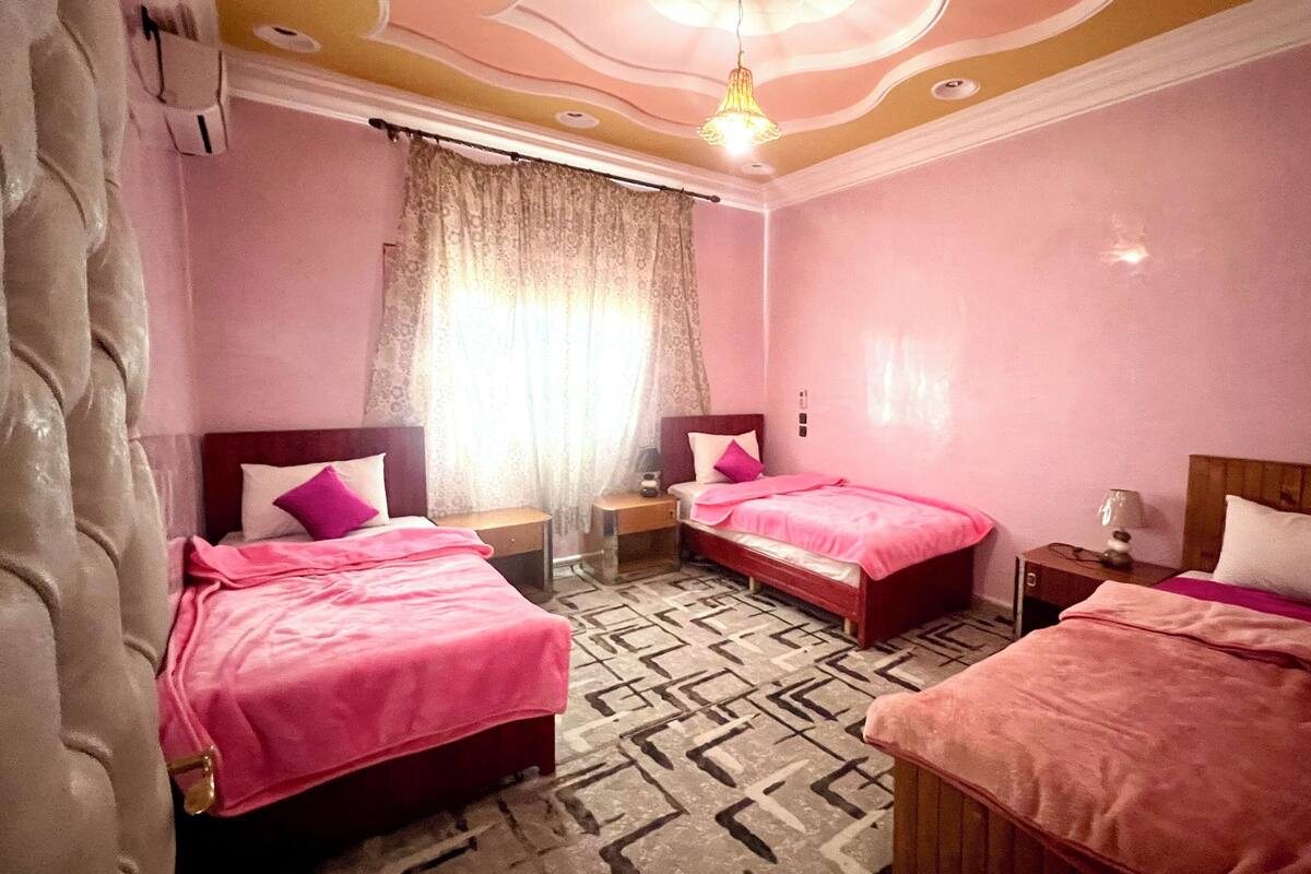 A hotel room with two beds, a patterned floor, and a chandelier.