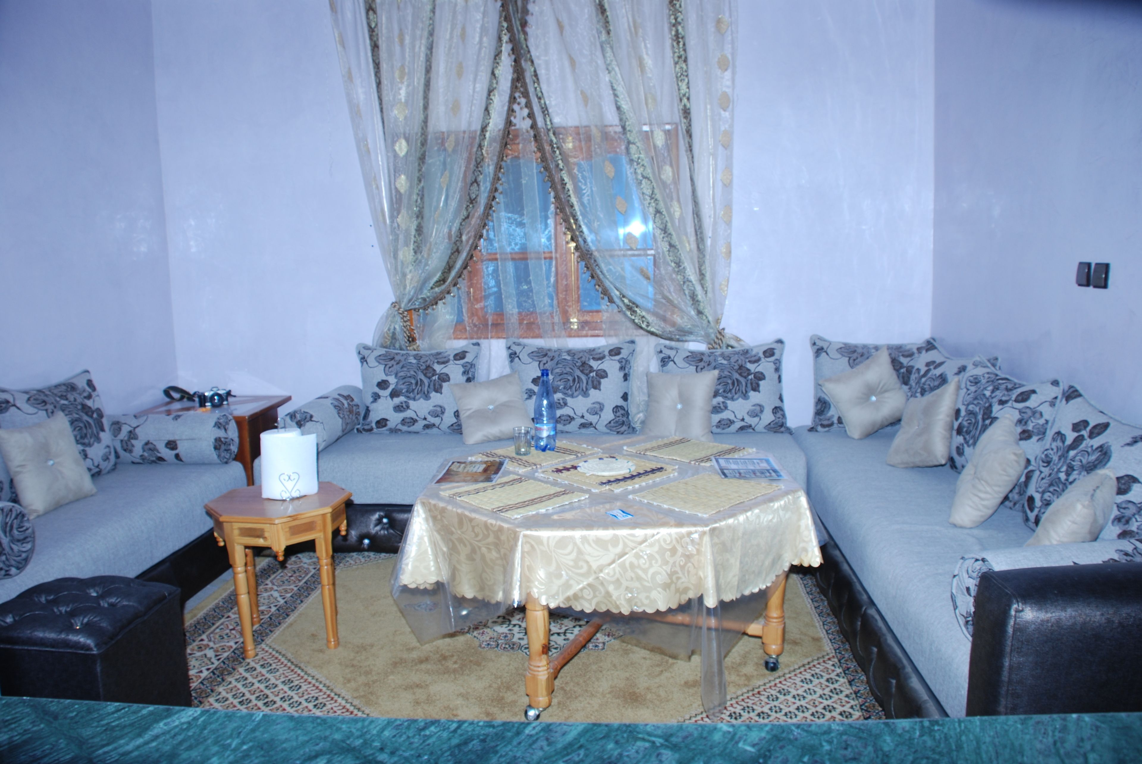 A living room with a sofa, a small table, and a window with curtains.